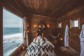 A person receiving a message wrapped in blankets in a cozy wood-sided room with a view of water outs